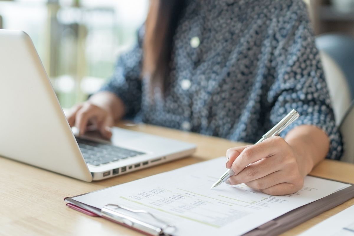 Mains saisissant au clavier et annotant un rapport papier chiffré
